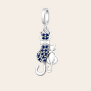 A silver cat-shaped pendant charm featuring one larger cat and one smaller cat, both detailed with sparkling blue stones, set against a clean white background.