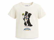 An off-white short-sleeve t-shirt featuring a cartoon illustration of a black and white dog holding a green tennis ball, with the text 'WHISKER FRIENDS' printed below.