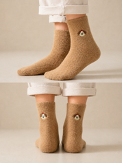 Person wearing brown socks with bear faces on a white surface