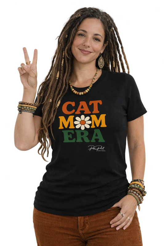 Woman wearing a black t-shirt with 'CAT MOM ERA' design, making a peace sign.