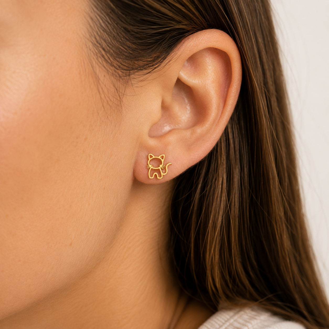 Close-up of a person wearing gold cat-shaped earrings.