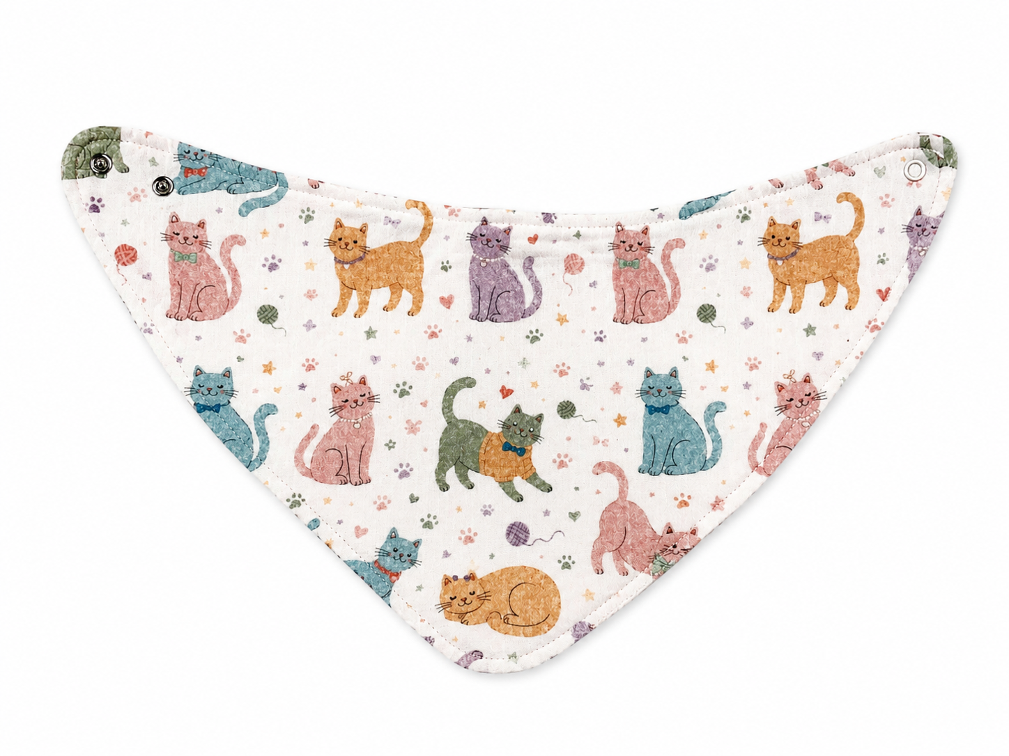 A triangular bandana bib with a white background and a colorful print of cartoon cats in various poses, decorated with tiny paw prints and hearts. It features snap buttons on the sides for fastening.