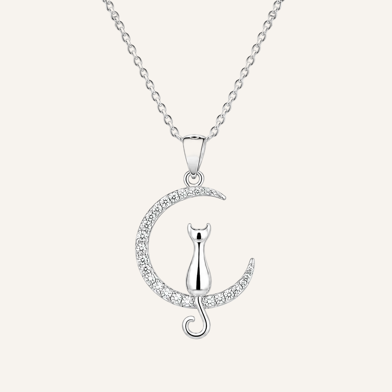 A silver pendant necklace featuring a polished cat silhouette sitting on a crescent moon adorned with small clear stones, suspended from a delicate silver chain against a white background.