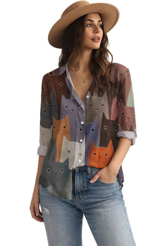 Woman wearing a patterned shirt with cat designs and a wide-brimmed hat on a white background