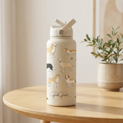 Water bottle with dog illustrations on a wooden table with a plant in the background