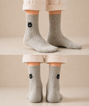 Person wearing light grey socks with black cat faces on a beige background