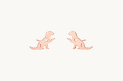 A pair of rose gold stud earrings shaped like sitting dogs, shown on a plain white background.