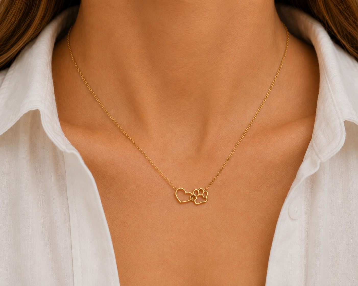 Gold necklace with heart and paw pendant worn by a person in a white shirt.