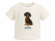 An off-white short-sleeve baby t-shirt featuring a cartoon illustration of a black and tan dachshund wearing a red collar with a gold badge, above the text 'WHISKER FRIENDS'.