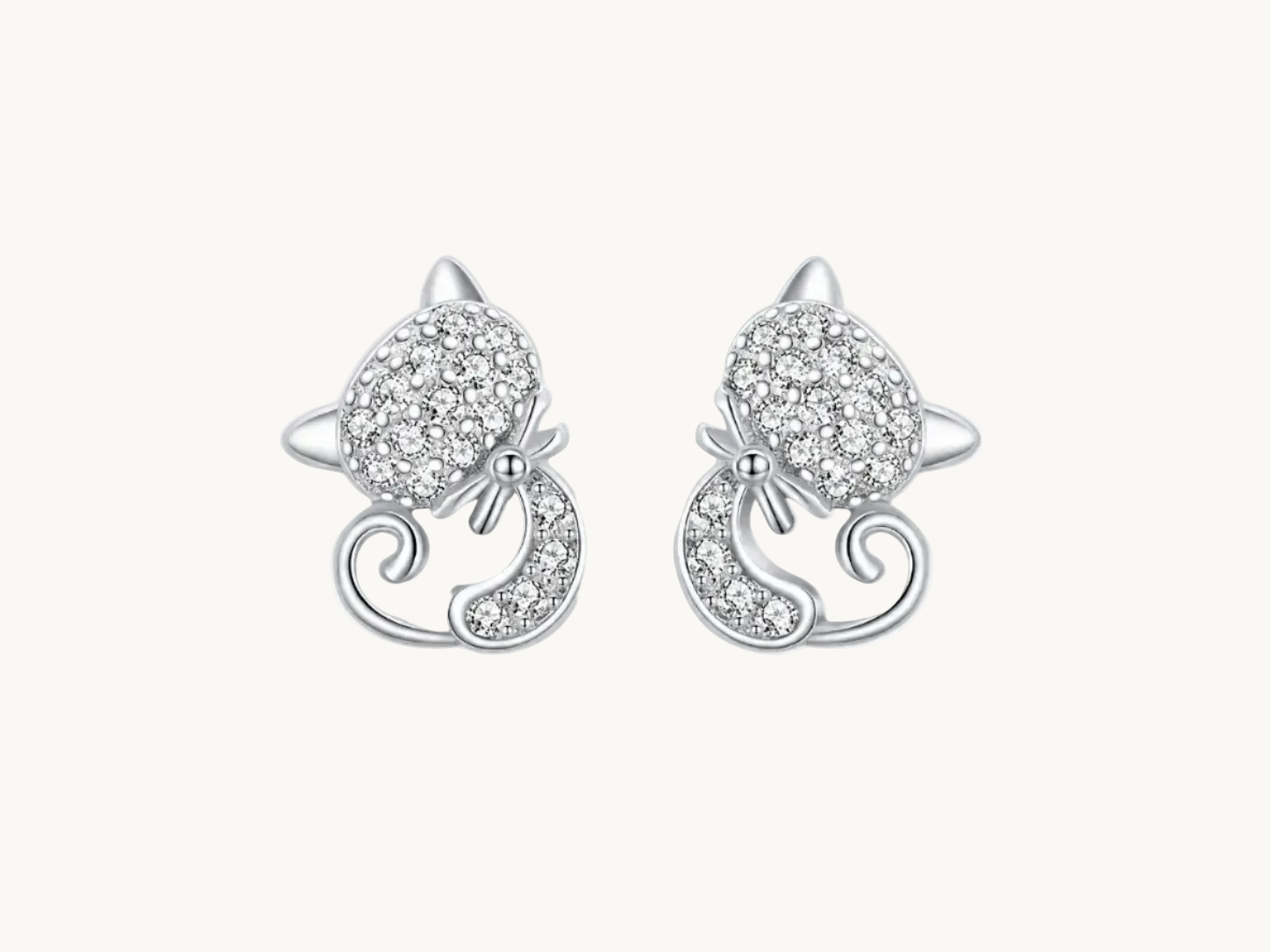 Silver cat-shaped earrings with clear gemstones on a white background