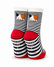 A pair of crew socks with black and white horizontal stripes, featuring a cartoon calico cat face near the cuff, red heels and toes, and the words 'KITTEN LOVE' printed on the sides.